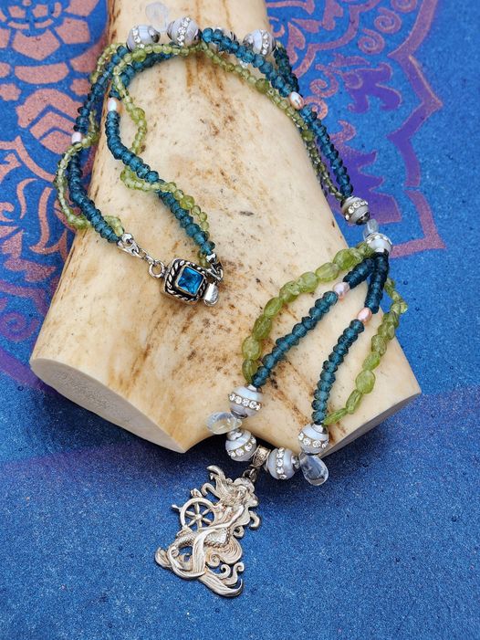 Captain of her own ship, this exquisite silver mermaid is a Buzzwinkle's exclusive on a peridot, topaz, pearl, and aquamarine double chain.